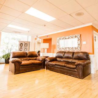 A well-lit living room with matching brown sofas and a large mirror on an orange accent wall.
