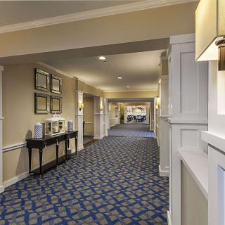 A well-decorated hotel hallway with patterned carpet and wall artwork.