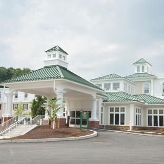 A building with a green roof and large entrance, set against a cloudy sky.