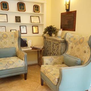 A cozy waiting area featuring elegant chairs, decorative awards on the shelf, and a touch of greenery.