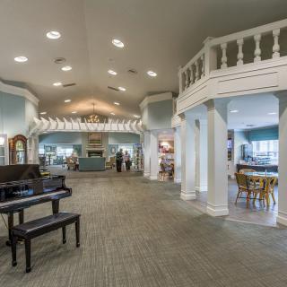 Spacious lobby interior featuring a grand piano, elegant columns, and a chandelier.