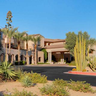 A desert resort with palm trees and cacti in the foreground.