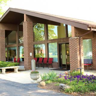 A modern brick building featuring large windows and a landscaped entrance.