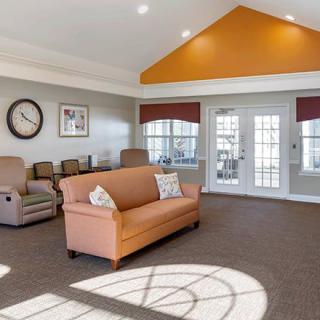A cozy and spacious living room with a sofa, recliners, and large windows letting in natural light.