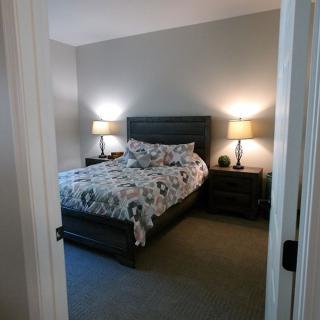 A cozy bedroom with a neatly made bed and warm lighting from two bedside lamps.