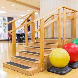 Physical therapy setup with wooden stairs and balance balls for rehabilitation exercises.