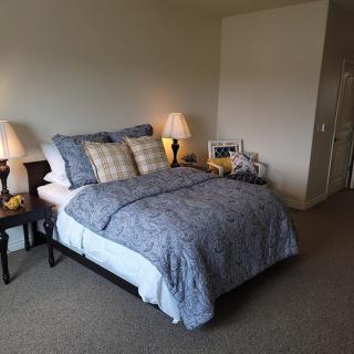 A cozy bedroom featuring a neatly made bed with blue bedding, accompanied by bedside tables and lamps.