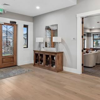 Spacious entryway with a hardwood floor, wooden console table, and mirror reflecting natural light.