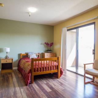 A modern minimalist bedroom with wooden furniture and ample natural light.