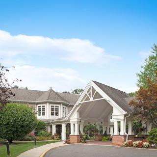 A quaint house surrounded by lush greenery under a blue sky.