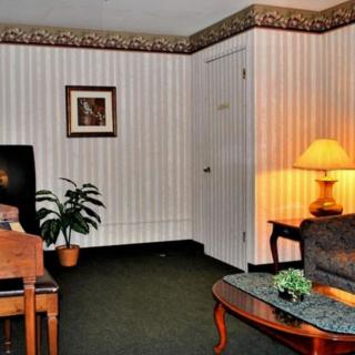 A cozy living room with a chair, sofa, coffee table, and a lamp casting a warm glow.