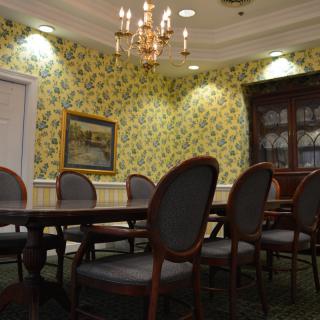 A classic conference room with a large table and chairs under a chandelier.