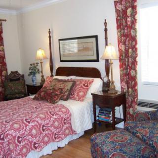 A cozy and inviting bedroom featuring a patterned bedspread and matching curtains.