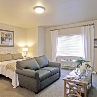 A cozy bedroom featuring a bed, a sofa, and a window with curtains.