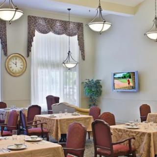 A spacious dining room with elegant chandeliers and neatly arranged tables.
