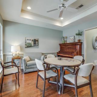 A cozy living room with a wooden piano, round table, and comfortable seating.