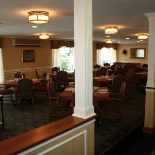 A cozy dining room with tables and chairs arranged neatly under warm lighting.