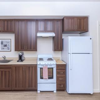 A modern kitchen with wooden cabinets, a white refrigerator, and a stove.