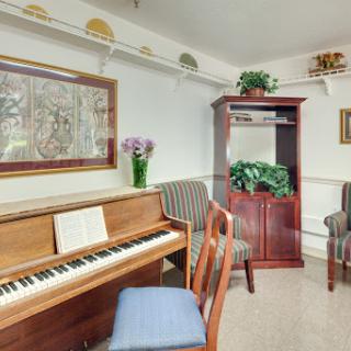 A cozy music room featuring a piano and comfortable seating, adorned with plants and artwork.