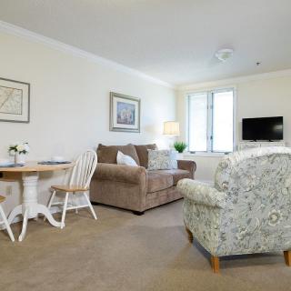 A cozy living room with a sofa, armchair, dining table, and television.