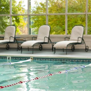 A serene indoor pool area with three lounge chairs by the side.