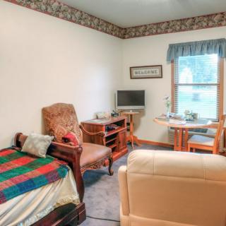 A cozy living room with comfortable seating, a television, and a window letting in natural light.