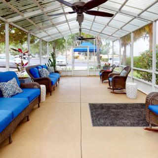 A cozy outdoor patio with blue-cushioned seating and a ceiling fan.