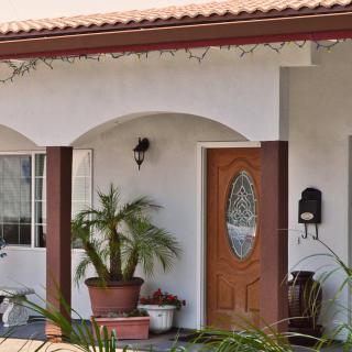 A cozy house entryway featuring a wooden door, potted plants, and arched porch design.