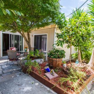 A charming patio area with lush greenery and outdoor seating next to a house.