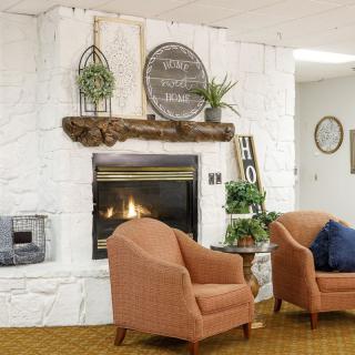 A cozy living room featuring a fireplace, comfortable armchairs, and decorative elements that create a warm atmosphere.