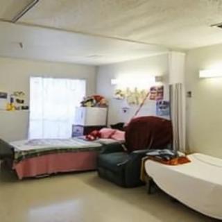 A well-lit hospital room featuring two beds and comfortable seating.