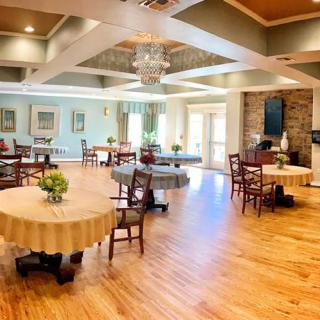 A spacious and elegantly decorated dining room with hardwood floors and round tables adorned with floral arrangements.