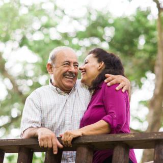 A joyful couple embracing on a wooden bridge surrounded by trees.