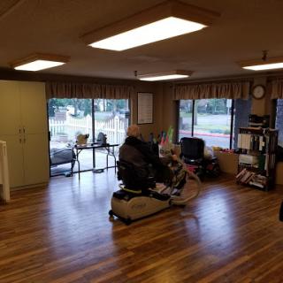 A spacious interior room with wooden flooring and large windows, filled with natural light.