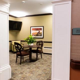 A cozy waiting area with a small table, two chairs, and decorative elements such as a painting and a television.