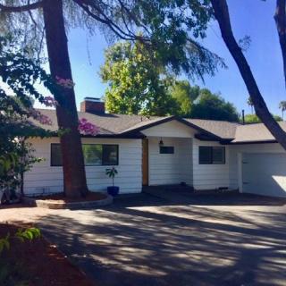 A suburban house surrounded by trees and a spacious driveway.