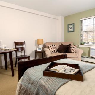 A cozy bedroom with a bed, sofa, and table setup in a neatly decorated space.