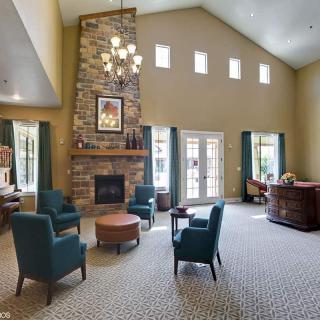 A spacious living room with high ceilings, featuring a stone fireplace and elegant furniture.