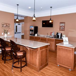 A modern kitchen with wooden cabinetry, bar stools, and pendant lighting.