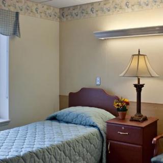 A cozy bedroom with a single bed, nightstand, and lamp.