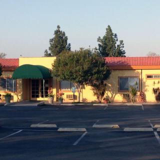 A restaurant with a green awning and surrounding trees on a sunny day.