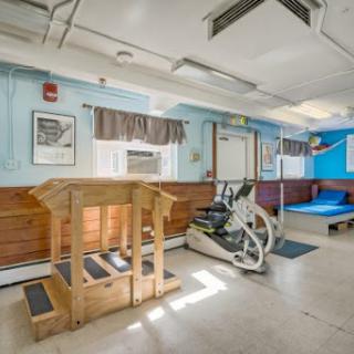 A bright and spacious gym area featuring exercise equipment and a wooden platform.