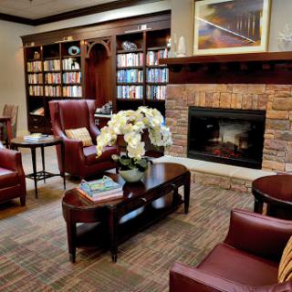 A cozy lobby area featuring comfortable chairs, a welcoming fireplace, and bookshelves filled with books.