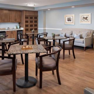 A cozy dining area with wooden tables and chairs, a sofa along the wall, and tasteful wall art.