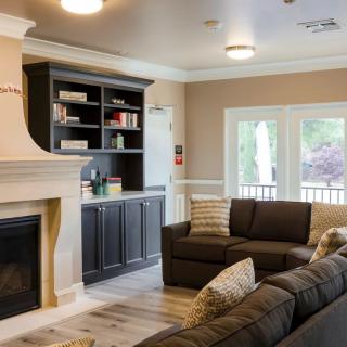 A modern living room featuring a cozy fireplace, dark sofas, and built-in shelving.