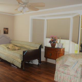 A cozy bedroom with a hospital bed, wooden floors, and large windows.