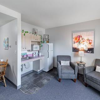 A cozy living area with comfortable chairs and a small kitchenette.
