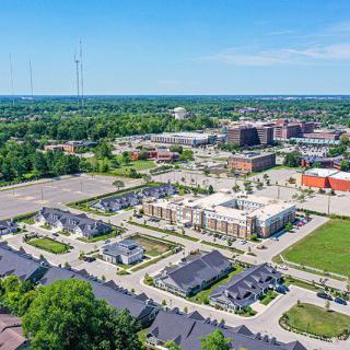 Aerial view of a mixed-use urban area featuring residential and commercial buildings with ample parking and surrounding greenery.