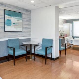 A modern waiting area featuring blue chairs, a small round table, and artwork on the wall.
