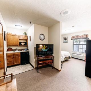A cozy studio apartment featuring a kitchenette and a small living area with a television.